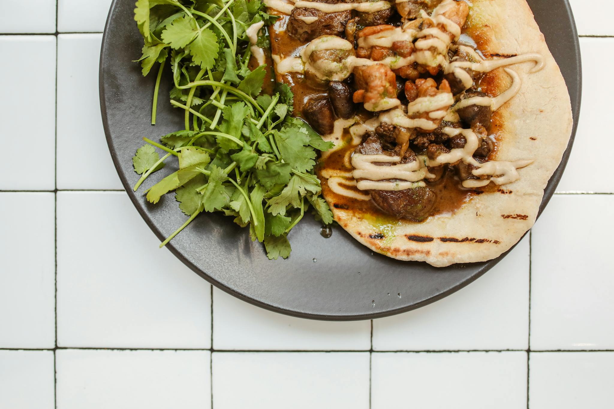 Close-up of a flavorful beef curry on roti with fresh herbs, perfect for a gourmet meal.