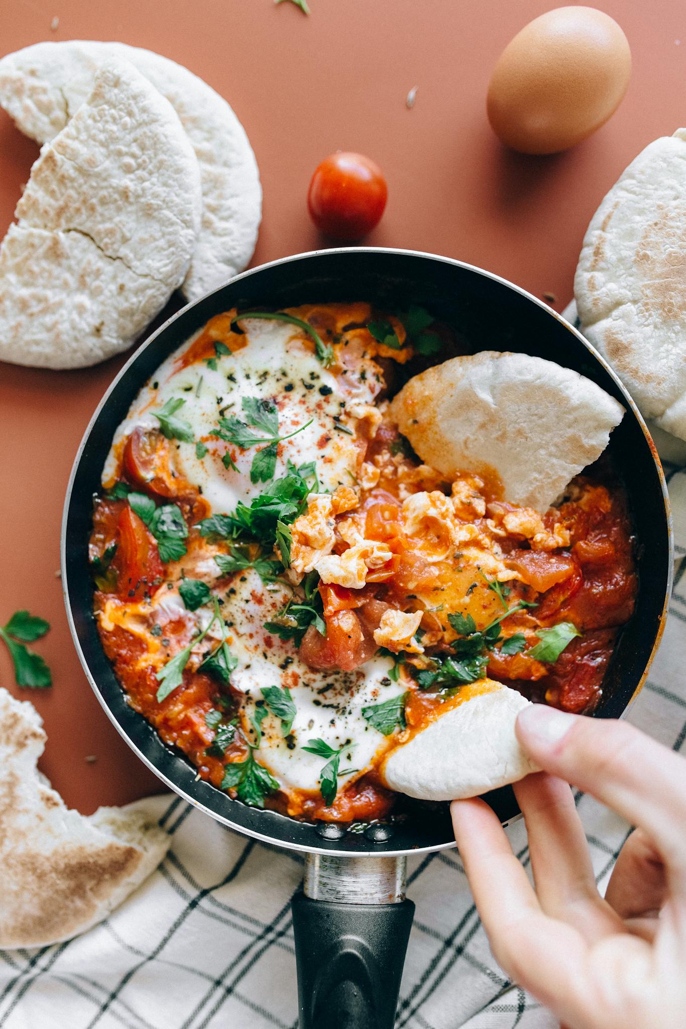 Savor a classic Shakshuka dish with vibrant tomatoes, eggs, and herbs served with fresh pita bread.